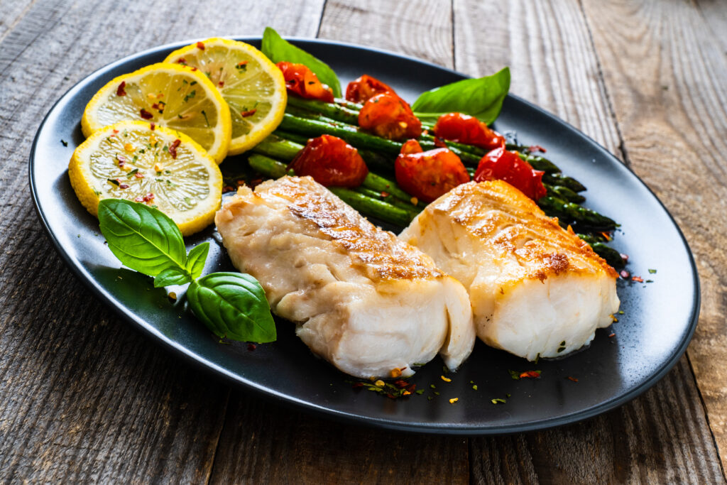 Gebratener Fisch am Teller mit Gemüse als Idee für Cholesterinärmere Ernährung