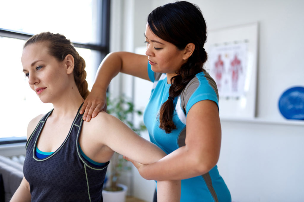 Physiotherapeut tastet Schulterschmerzen ab