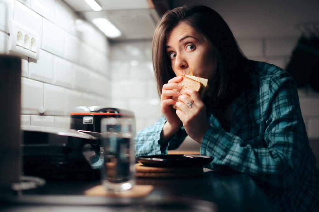 Frau isst Sandwich in der Nacht