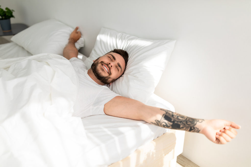 Mann wacht im Bett auf