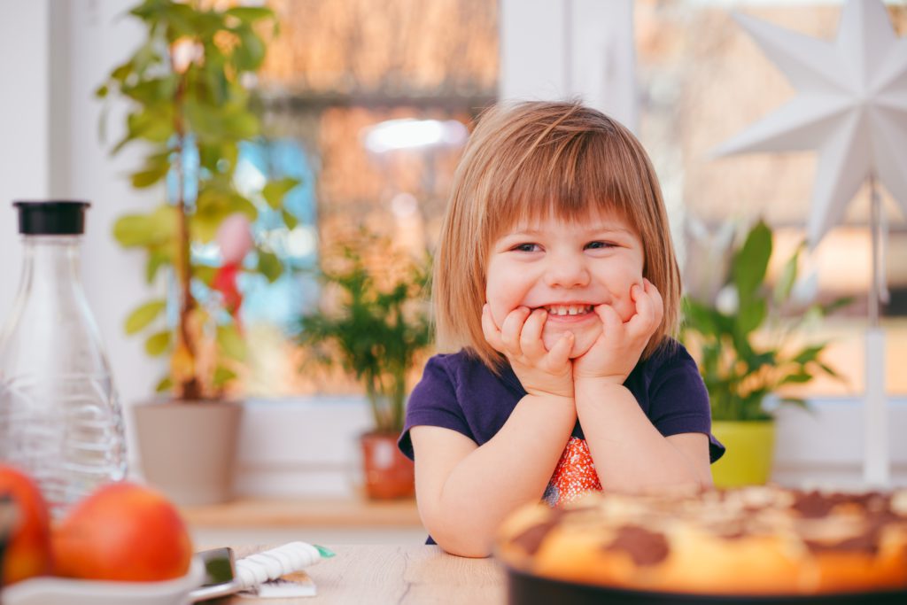 Kind sitzt am Tisch und freu sich auf Essen